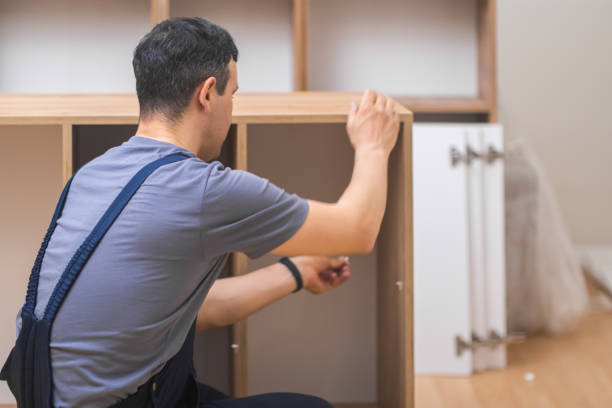 istockphoto-1498233807-612×612 Furniture production company focused man in uniform screwing nails into shelves of wooden rack designed for modern office interior professional carpentry work